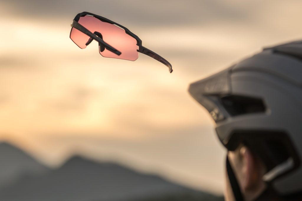 Biciklističke naočale sa crvenim staklima lebde u zraku kraj biciklista