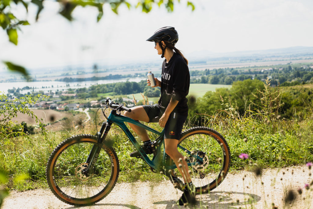 Žena sjedi na brdskom biciklu CTM zelene boje i gleda u prirodu s pogledom na grad