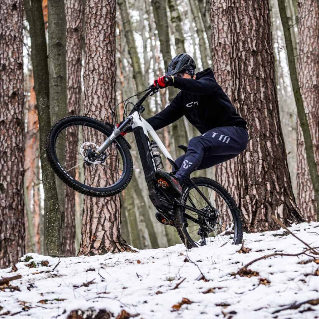 Biciklist u šumi vozi po zadnjem kotaču na snijegu
