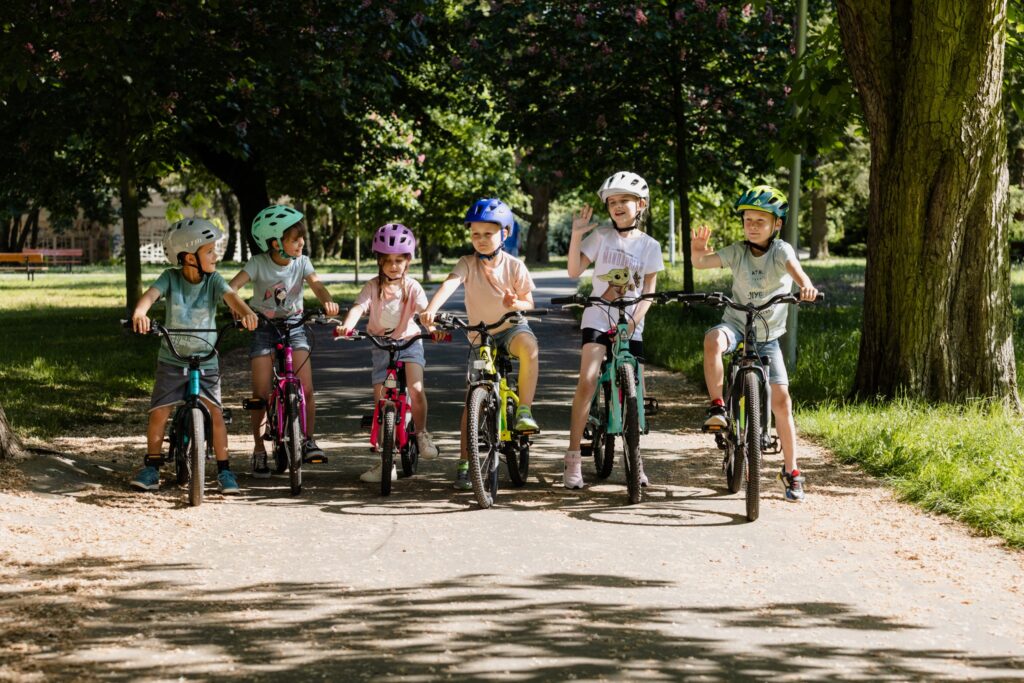 Dječji bicikli za sve uzraste u raznim bojama. Djeca u parku na biciklima